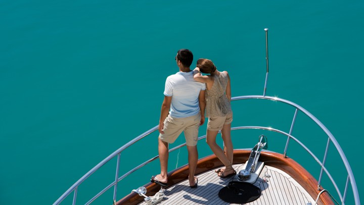 A couple on a yacht looks out at the water.
