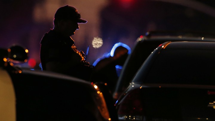 The silhouette of a police officer stopping a car