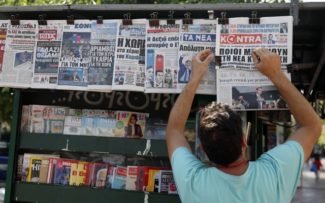 A vendor adjusts the front pages of the Greek newspapers, which refer to the election result