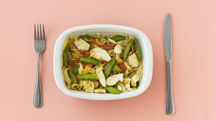 A microwave-dinner plate of pasta with chicken and vegetables
