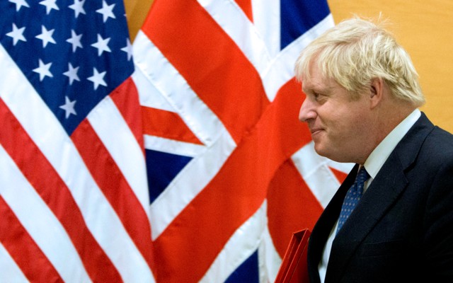 Boris Johnson walks past the flags of the United States and the United Kingdom.