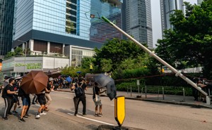 Protesters in Hong Kong take down a lamppost