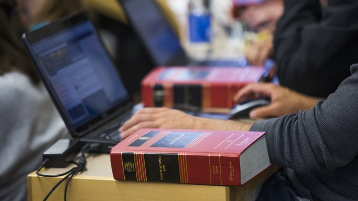 A student working on a laptop with a textbook nearby.