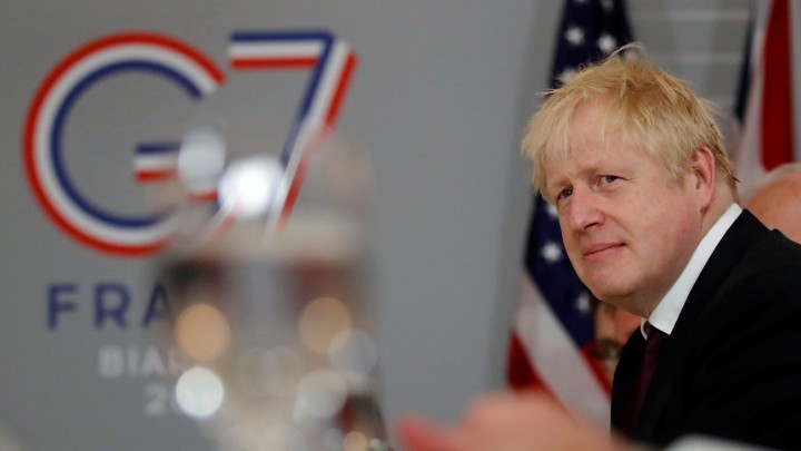 Boris Johnson stands in front of a sign for the G7 in Biarritz.