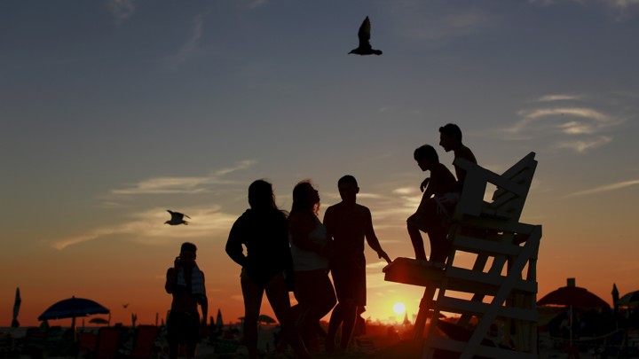 Kids are seen in silhouette at sunset on the beach in Atlantic Beach, New York, on September 6, 2015.