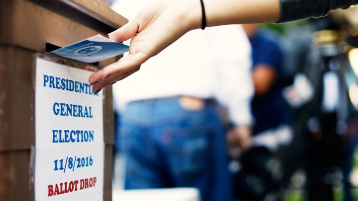 A voter dropping a ballot into a ballot box