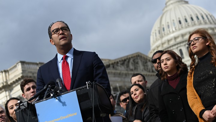 Representative Will Hurd of Texas stands at a podium outside the U.S. Capitol in Washington, D.C. Behind him are 10 men and women watching him speak. The Capitol dome is visible in the background.