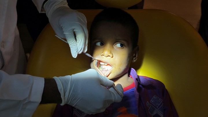 A dentist examines the inside of a young boy's mouth.