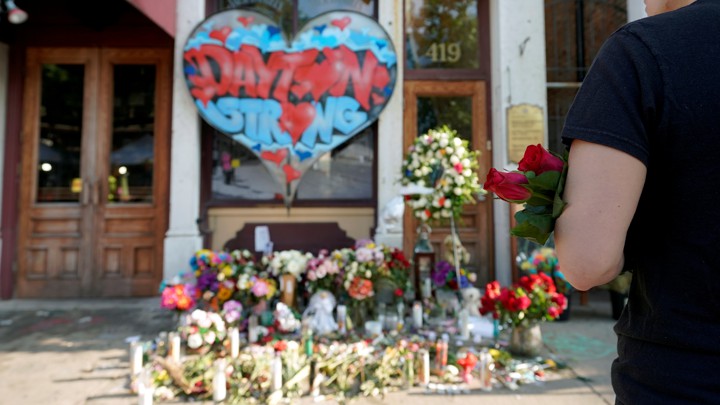 A person stands with roses in their arms before a memorial for those killed during a mass shooting in Dayton, Ohio.