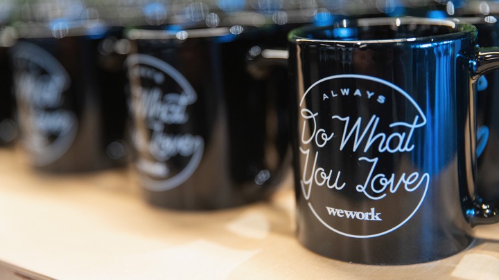 A row of coffee mugs imprinted 'Always Do What You Love — WeWork'