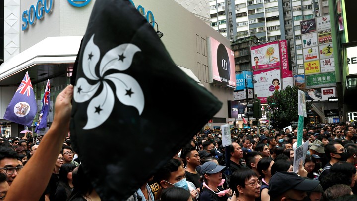 A protester holds up a black version of Hong Kong's flower-emblazoned flag during a packed pro-democracy rally.
