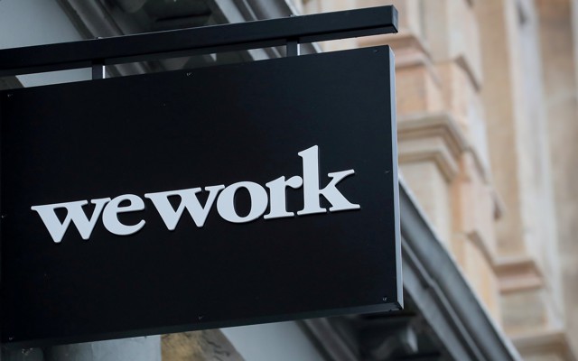A WeWork sign against some tan buildings