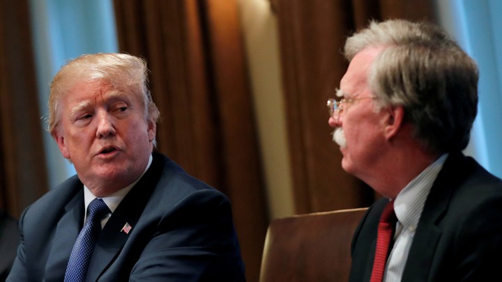 Donald Trump crosses his arms as he speaks with John Bolton.