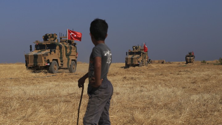 Turkish armored vehicles conduct a joint ground patrol with American forces in the "safe zone" on the Syrian side of the border with Turkey