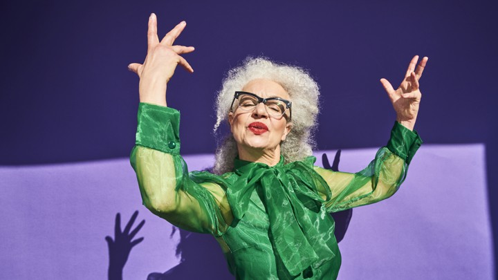 A confident-looking woman holds her arms in the air.