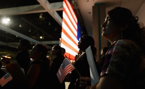 U.S.-citizenship candidates look at a video presentation as they wait to take the oath of citizenship at a naturalization ceremony.