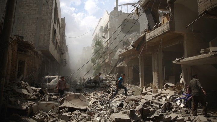 Syrians walk amid the rubble of destroyed buildings
