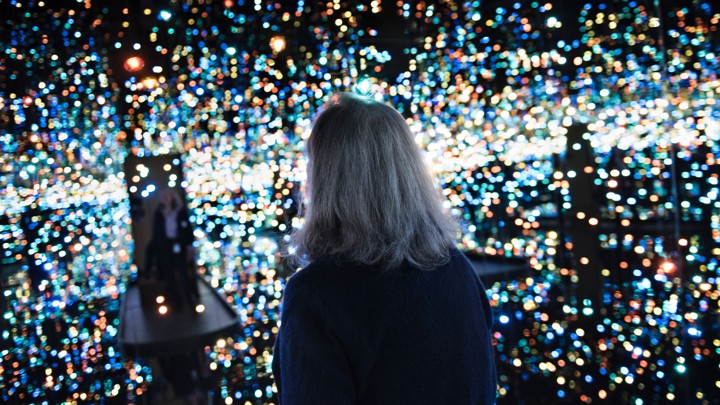 A woman alone in an art installation with hundreds of tiny lights and mirrored walls.