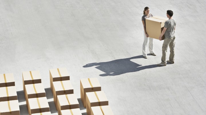 A man and a woman carrying a box together.