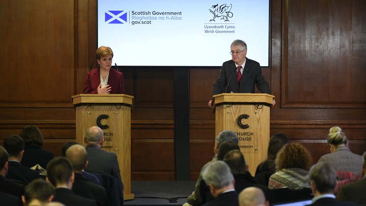 Nicola Sturgeon and Mark Drakeford stand at podiums while delivering a press conference.