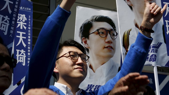 Edward Leung stands next to a poster representing him.