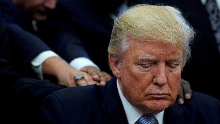 Pastors lay hands on President Donald Trump in prayer in the Oval Office.