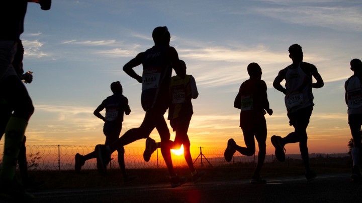Silhouettes of people jogging along a road