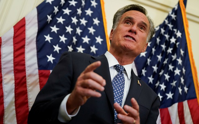 Mitt Romney stands in front of two American flags.
