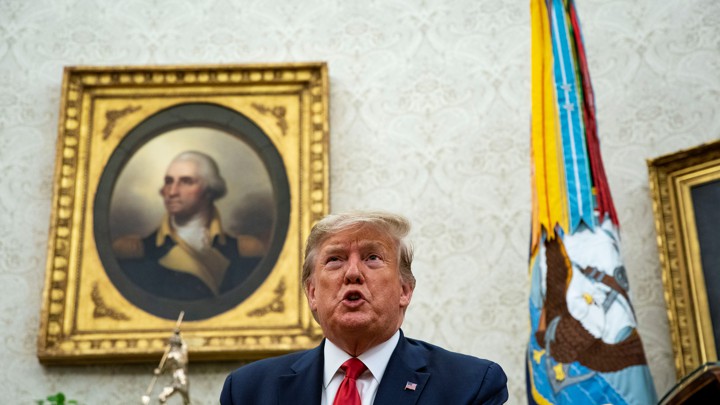 Trump sits in the Oval Office in front of a portrait of George Washington.