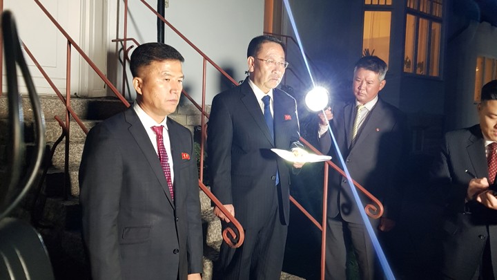 Kim Myong Gil stands on the steps of the North Korean embassy holding a paper.