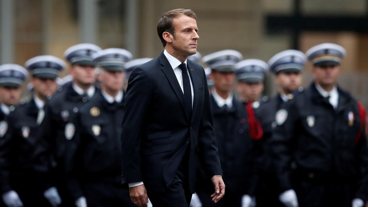 Emmanuel Macron walks past a line of police officers in formation during a ceremony to honor the four victims of the Paris police-headquarters killings.