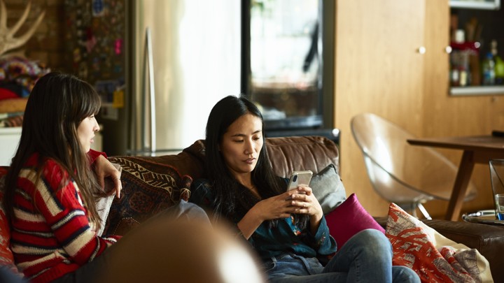 celebrity crush Two women on a sofa; one is holding a phone.