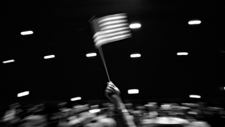 Black-and-white image of a person waving an American flag