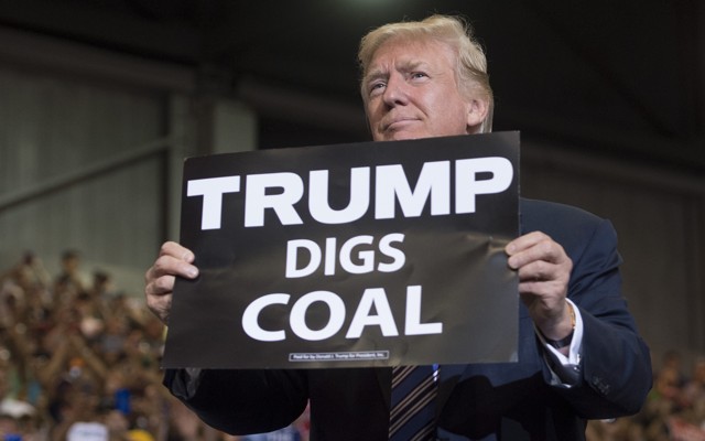 President Donald Trump holds up a "Trump Digs Coal" sign as he arrives to speak during a Make America Great Again Rally at Big Sandy Superstore Arena in Huntington, West Virginia, August 3, 2017