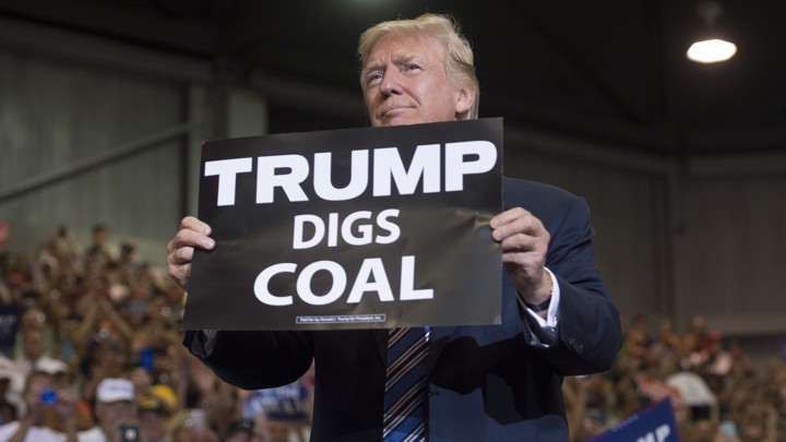 President Donald Trump holds up a "Trump digs coal" sign as he arrives to speak during a Make America Great Again rally at Big Sandy Superstore Arena in Huntington, West Virginia, on August 3, 2017.