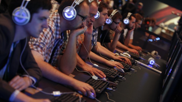 People sit with headphones on staring at computer screens.