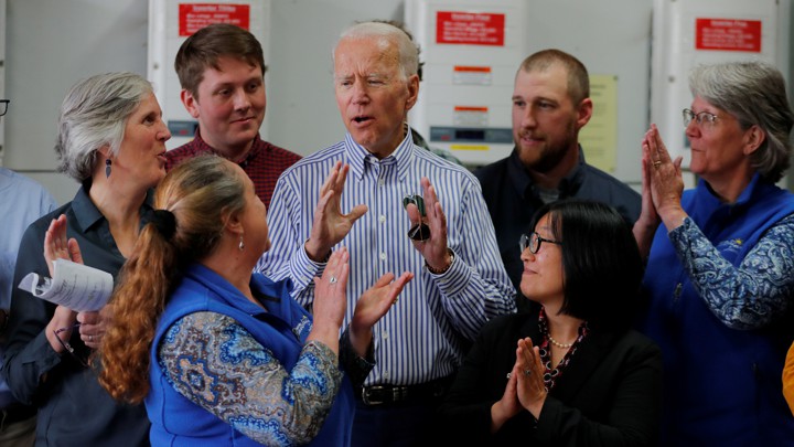 Joe Biden speaks surrounded by a circle of staff members and supporters.