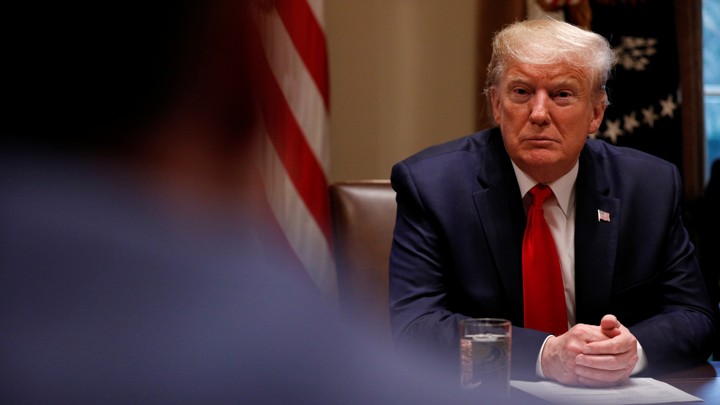 Trump sits with his hands clasped together.