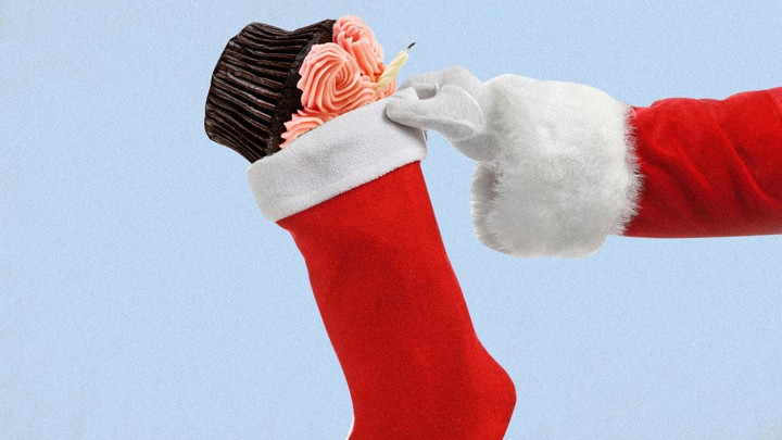 An illustration of a birthday cupcake being placed into a Christmas stocking.