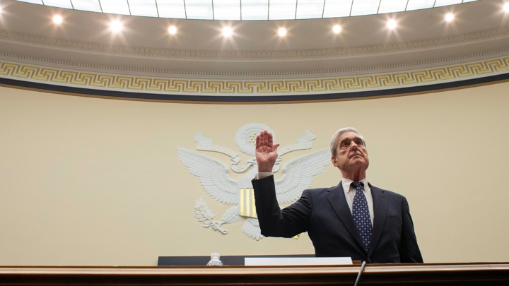 Robert Mueller lifts his right hand up while swearing in to testify in front of the House Judiciary Committee.