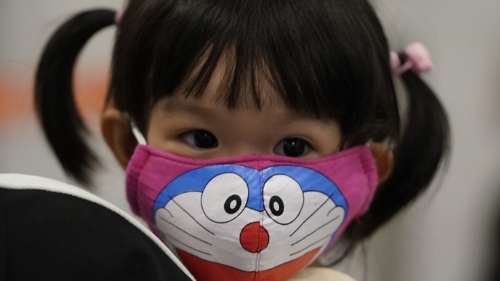 A young passenger wears a face mask as she waits at the immigration counter in Malaysia.