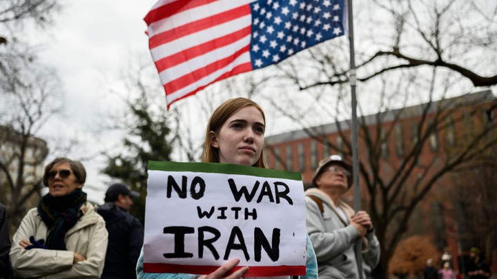 A protester holds a sign reading "No war with Iran."