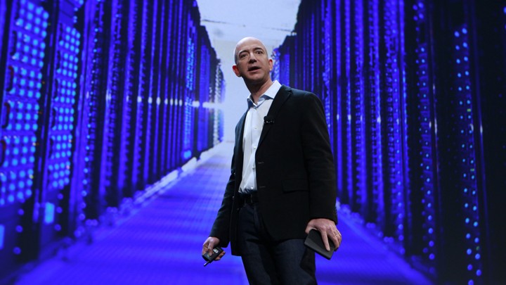 Jeff Bezos stands in front of a purple, blue, and black data center.