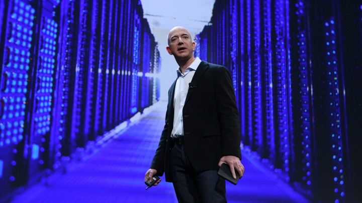 Jeff Bezos stands in front of a purple, blue, and black data center.