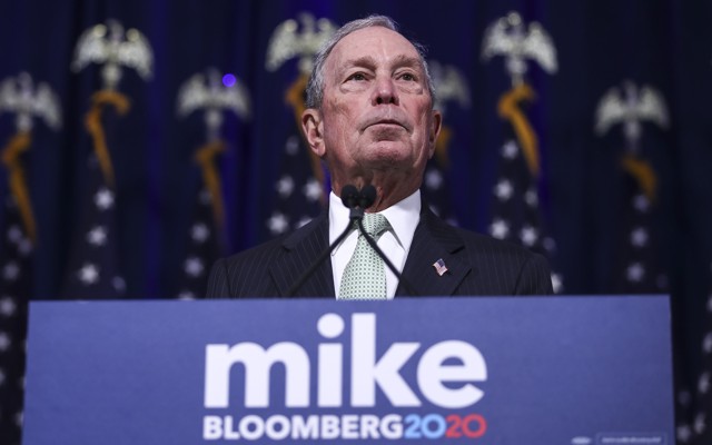 Michael Bloomberg stands at a lecturn.