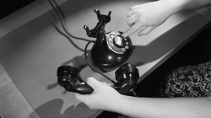 A woman's hand dials an antique phone.