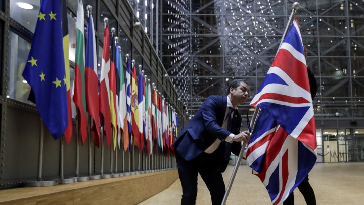 A person removes the British flag from a hall with European flags.