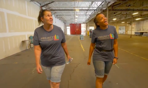 Two women involved with Project Lia look up at windows they helped restore.