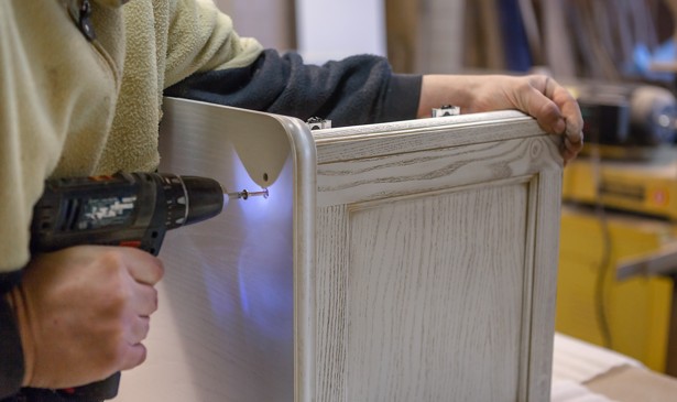 A man drills into wood as he makes furniture