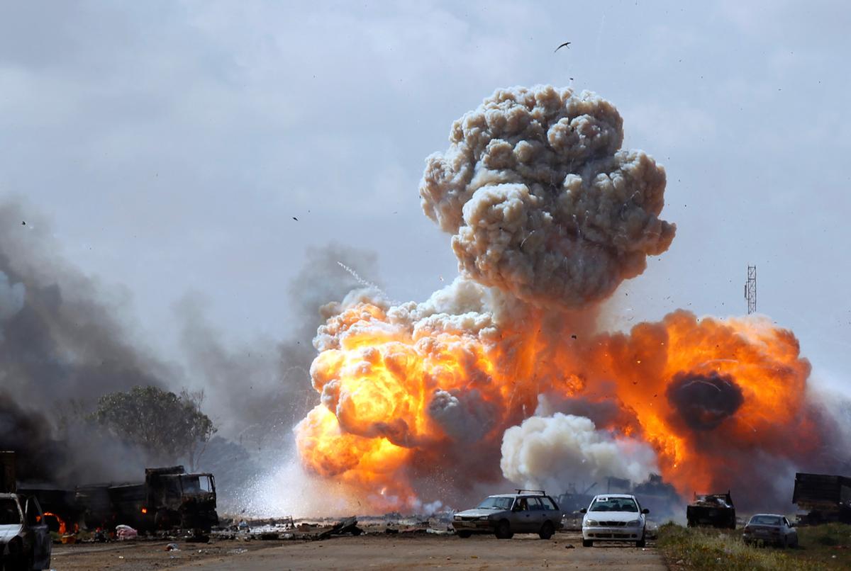 (Vehicles belonging to forces loyal to Libyan leader Muammar Qaddafi explode after an air strike by coalition forces, along a road between Benghazi and Ajdabiyah March 20, 2011 © Reuters/Goran Tomasevic)